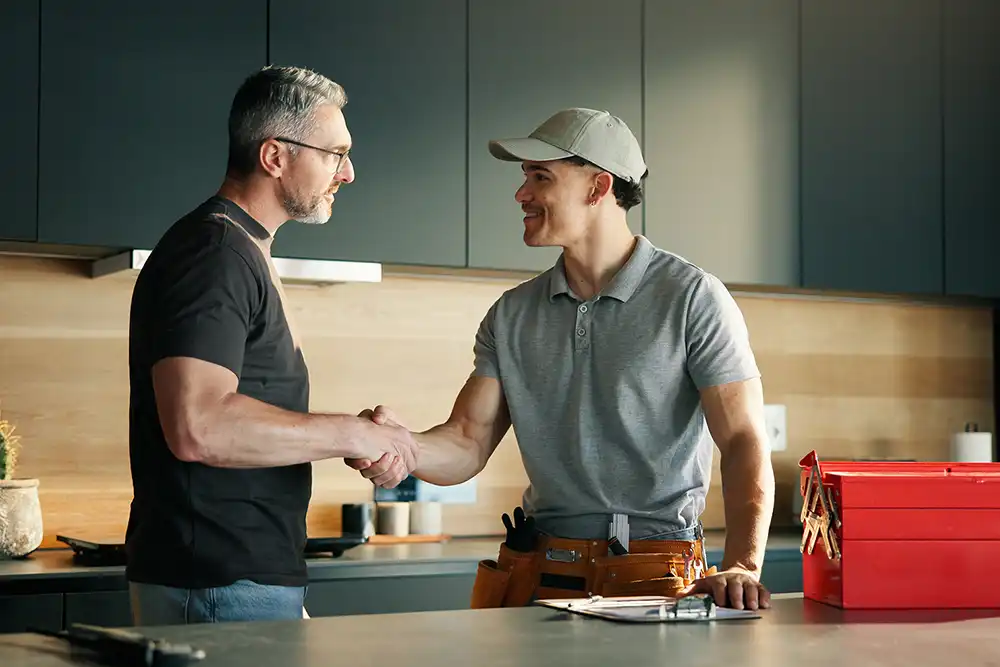 Männer, Klempner und Kunde geben sich in der Küche die Hand, um eine Lösung, Wartungsarbeiten und die Reparatur eines Lecks zu vereinbaren. Hausbesitzer, Handwerker und Händeschütteln im Haus, um Hilfe zu erhalten, die Arbeit abzuschließen und sich für den Vor-Ort-Service zu bedanken.